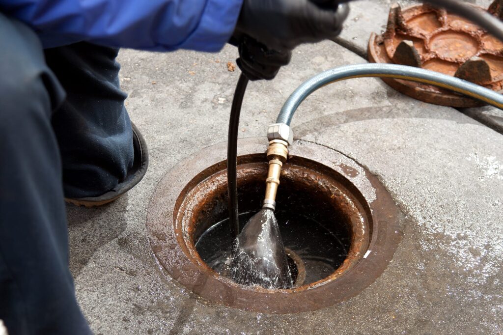 Plumber hydro jetting a sewer line through a manhole in Bullhead City